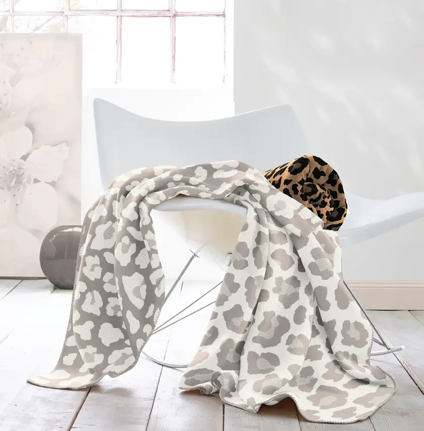 Dekorativer Designstuhl mit gemusterter Kuscheldecke und Kissen im Leoparden-Look – modernes Wohnaccessoire für gemütliches Wohnzimmer, stilvolle Einrichtung und trendige Textilien.